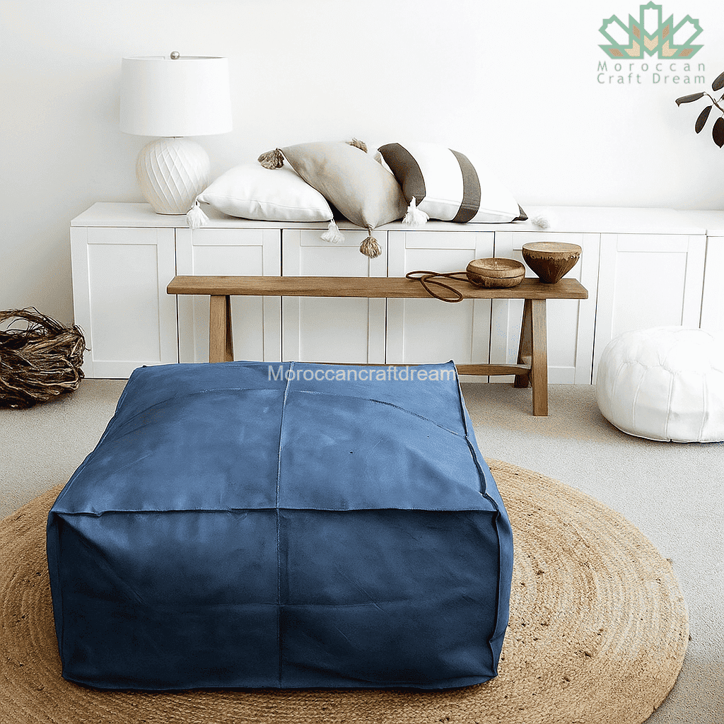 Blue leather ottoman coffee table in a living room setting with a wooden bench and decorative items.