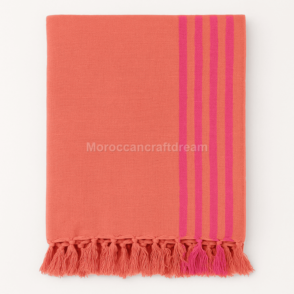 Coral towel with pink stripes and fringes on a white background, branded 'MoroccanCraftDream'.
