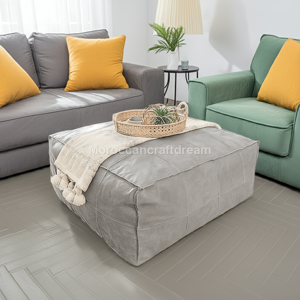 Gray leather ottoman coffee table with a woven basket on top, surrounded by gray and green sofas with yellow cushions in a living room setting.