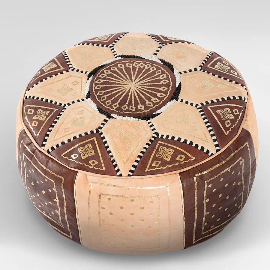 Handcrafted round leather ottoman used as foot stool coffee table or pouf with intricate Moroccan design, perfect for adding a touch of artisanal elegance to modern or bohemian home decor.