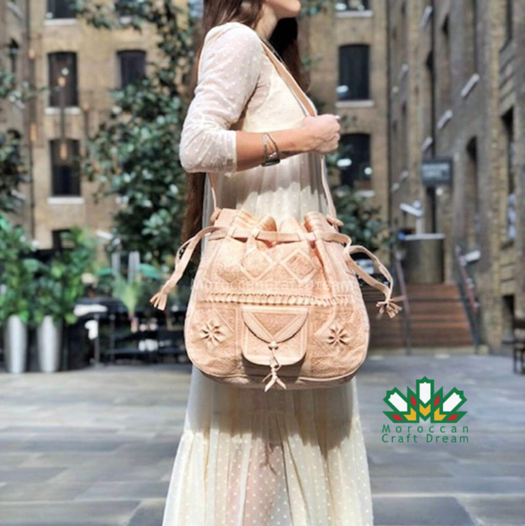 Woman holding a beige embroidered bag in an urban setting