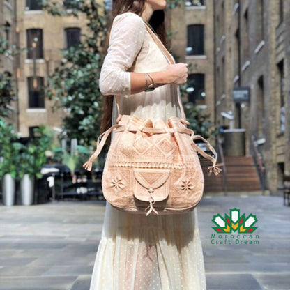 Woman holding a beige embroidered bag in an urban setting