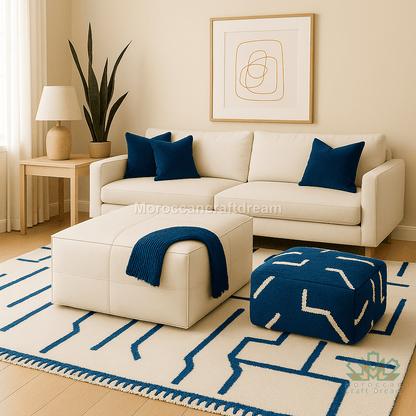 Modern living room with a beige sofa, blue cushions, and a matching ottoman on a geometric rug.
