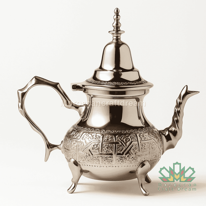 Silver teapot with intricate designs on a white background
