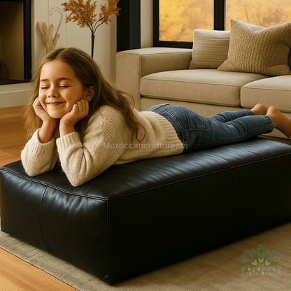 Young girl lying on a black leather ottoman in a cozy living room.