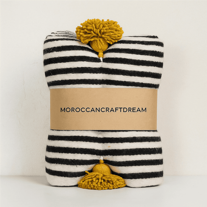 Striped fabric with pom-poms and 'Moroccancraftdream' label on a white background