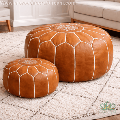 Caramel leather ottomans with white embroidery on a textured rug placed in bright open living space
