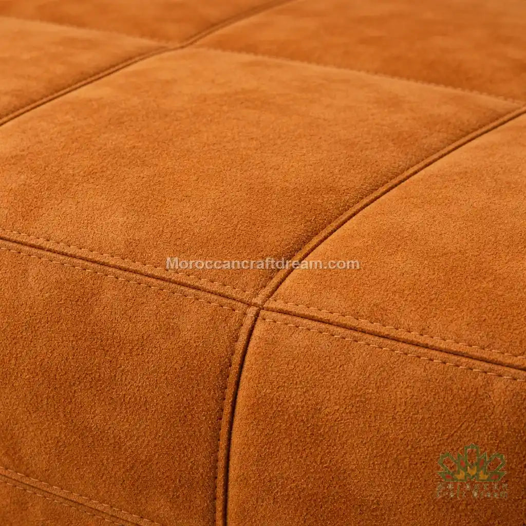 Close-up of a caramel leather ottoman with visible stitching, brand name 'MoroccanCraftDream' in the corner.