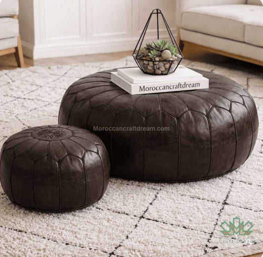 Two dark brown leather ottomans on a textured rug with a decorative bowl and books on top.