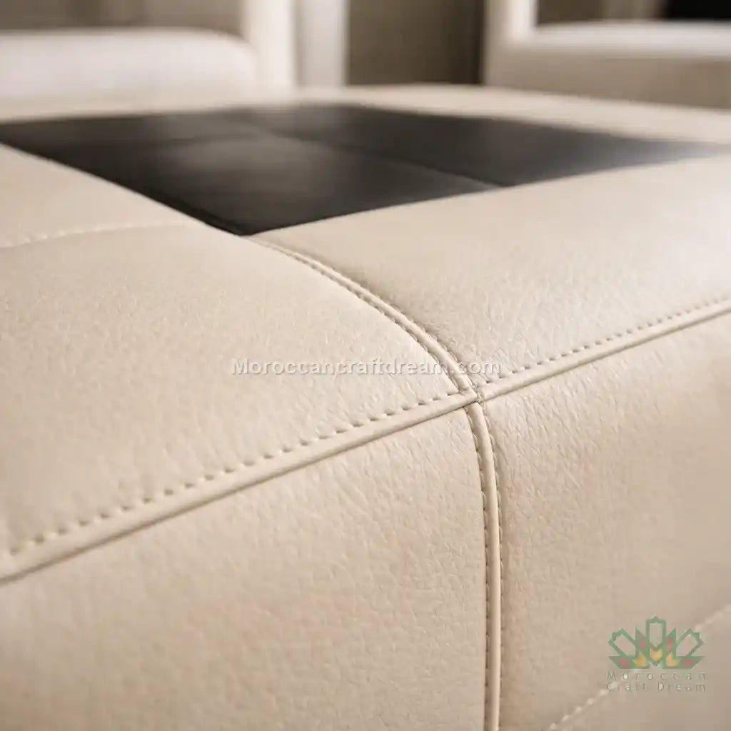 Close-up of beige leather furniture with visible stitching, brand logo in the corner.