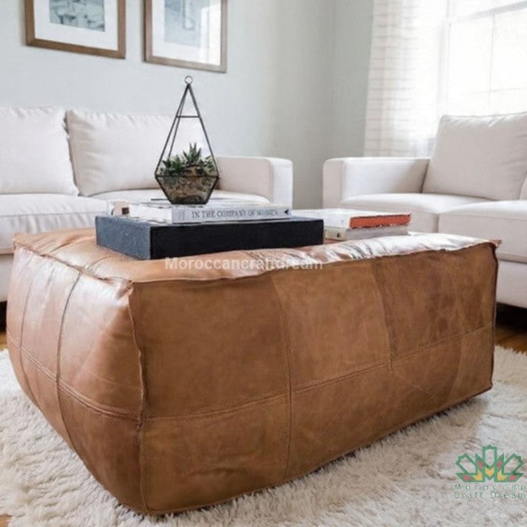 Brown light caramel leather ottoman in a living room setting with white sofas and decor.