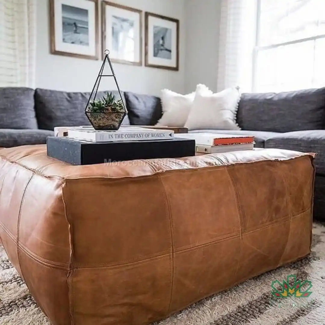 extra large leather ottoman coffee table in a living room with a gray sectional sofa and decorative items.