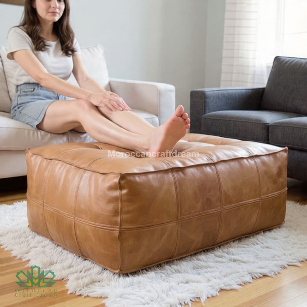 Woman sitting on a brown leather ottoman in a living room.