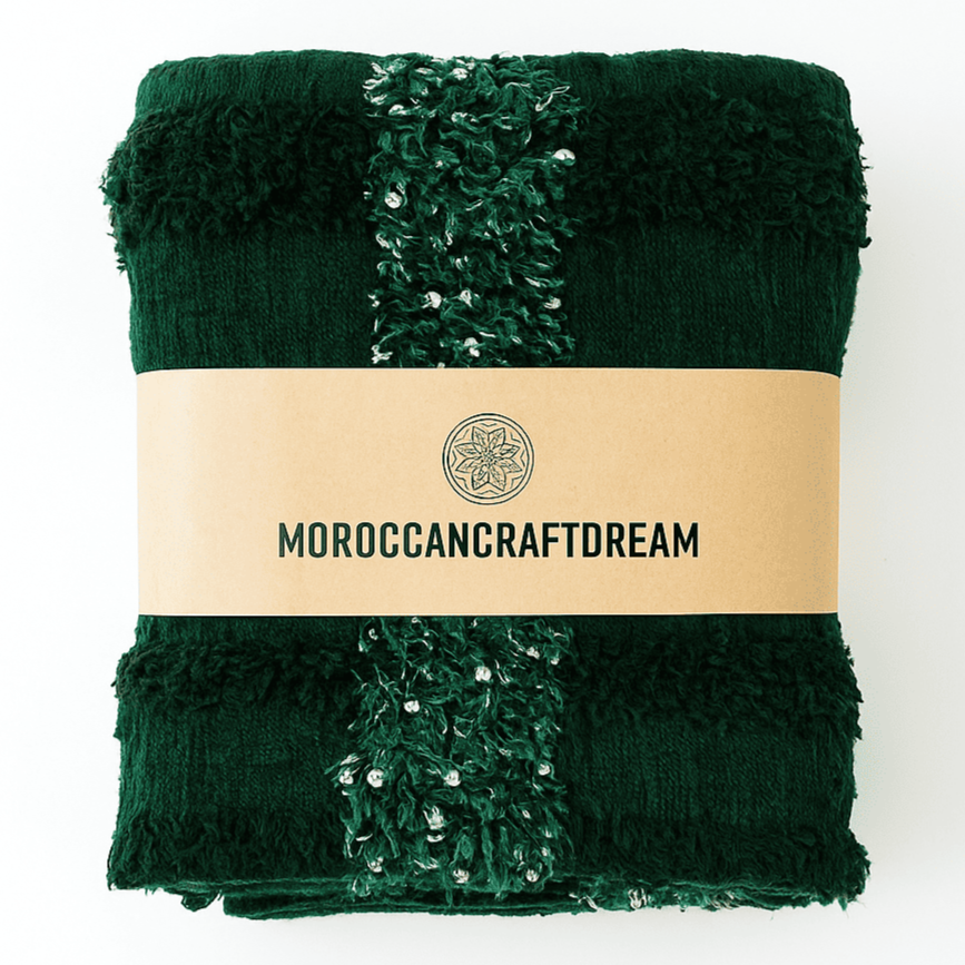 Folded green blanket with textured edges and a visible brand label on a white background