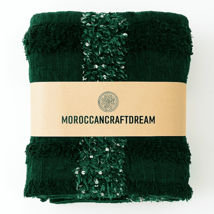 Folded green blanket with textured edges and a visible brand label on a white background