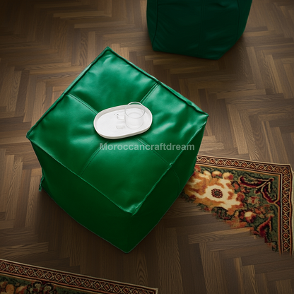 Green ottoman with a white label on a wooden floor, featuring the brand 'MoroccanCraftDream'.