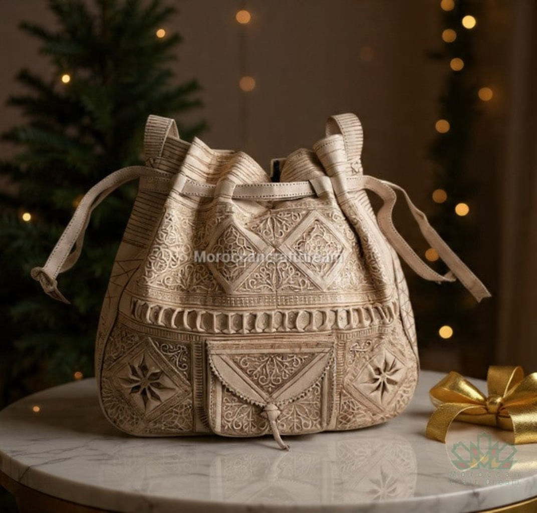Decorative beige bag with intricate patterns on a marble surface with a blurred festive background.