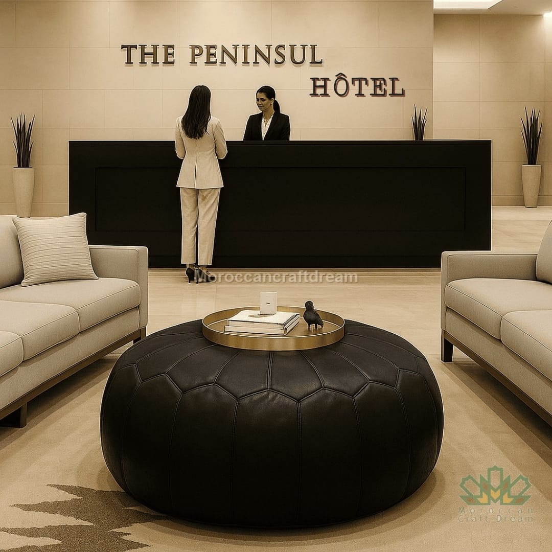 Two women at a reception desk in a hotel lobby with 'The Peninsul Hotel' sign and black leather ottoman.
