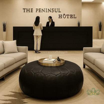 Two women at a reception desk in a hotel lobby with 'The Peninsul Hotel' sign and black leather ottoman.