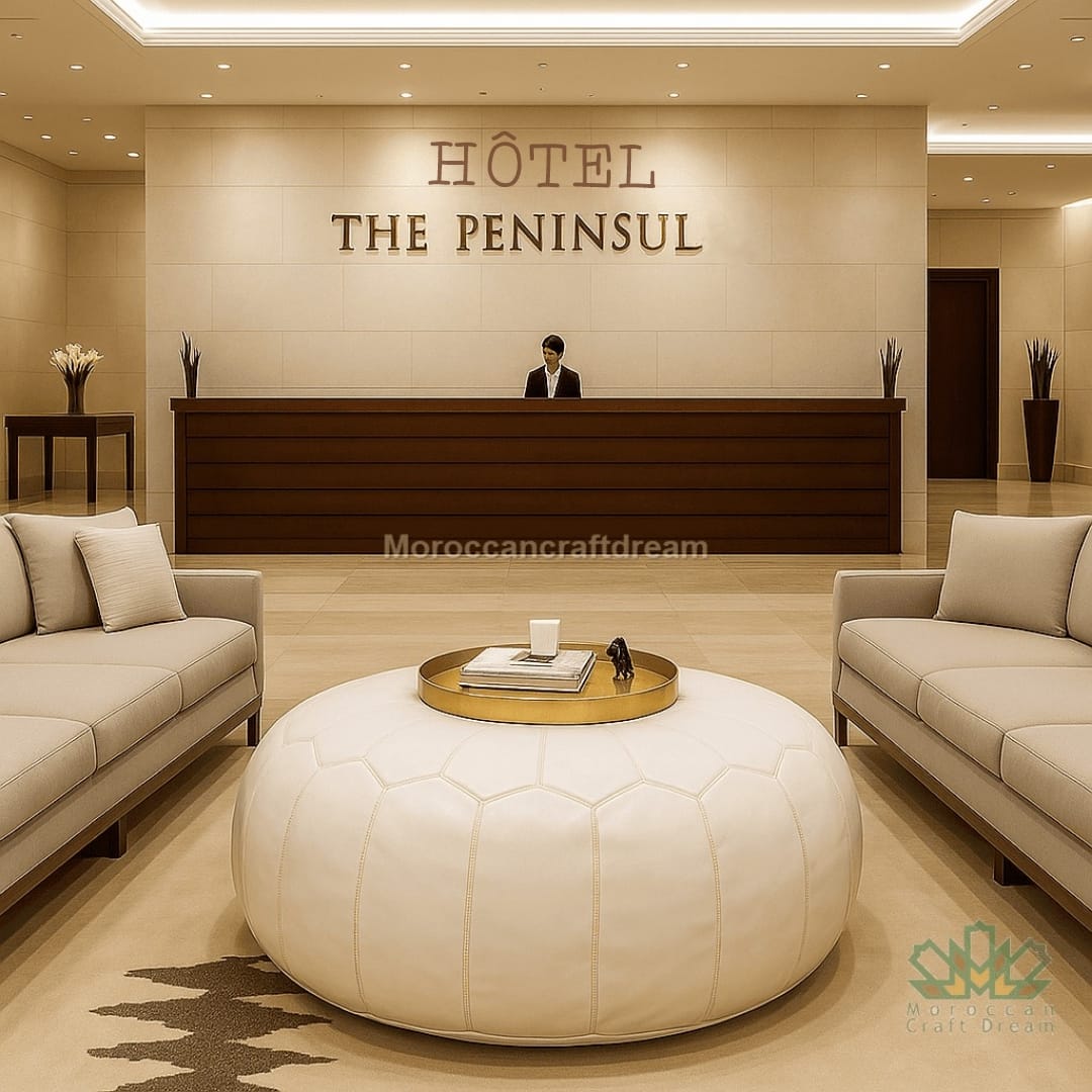 Hotel reception area with 'The Peninsula' sign and beige interior design and white leather ottoman.