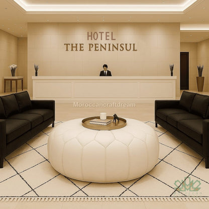 Hotel reception area with 'The Peninsula' sign, black couches, and a white leather ottoman.