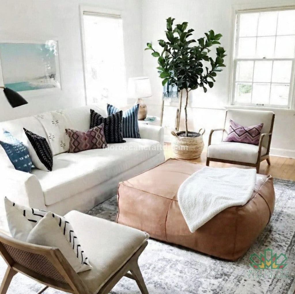 Living room with white sofa, light caramel ottoman, and decorative pillows.