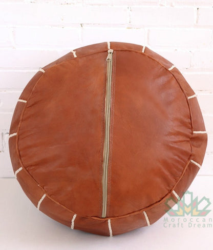 Luxurious tan brown leather Moroccan pouf ottoman by Moroccancraftdream, used as a footrest or extra seating option.