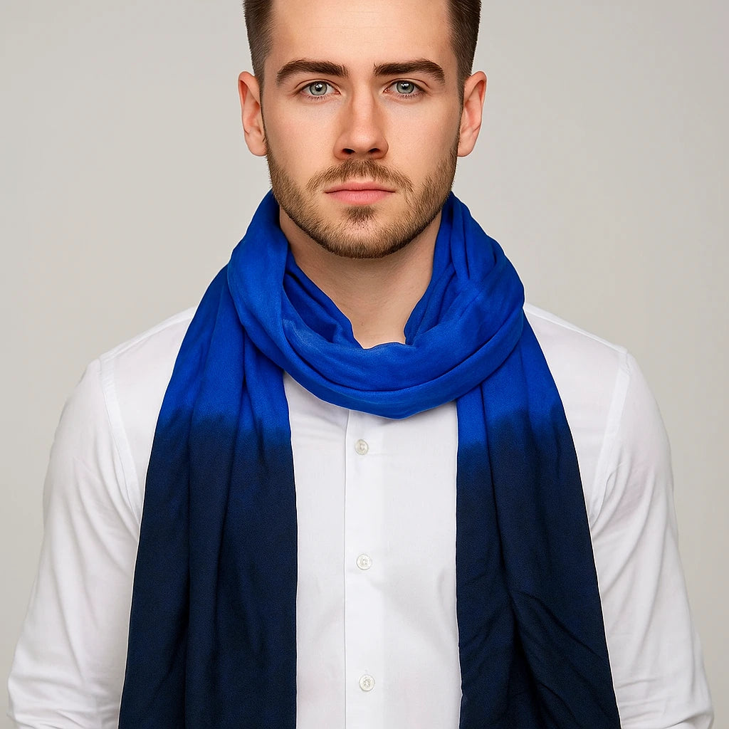 Man wearing a blue scarf over a white shirt against a plain background
