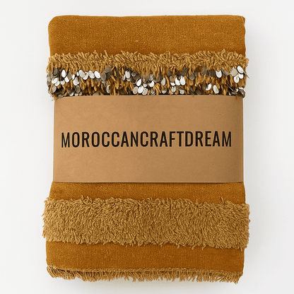 Brown textured blanket with decorative trim on a cardboard label displaying 'MOROCCANCRAFTDREAM'.