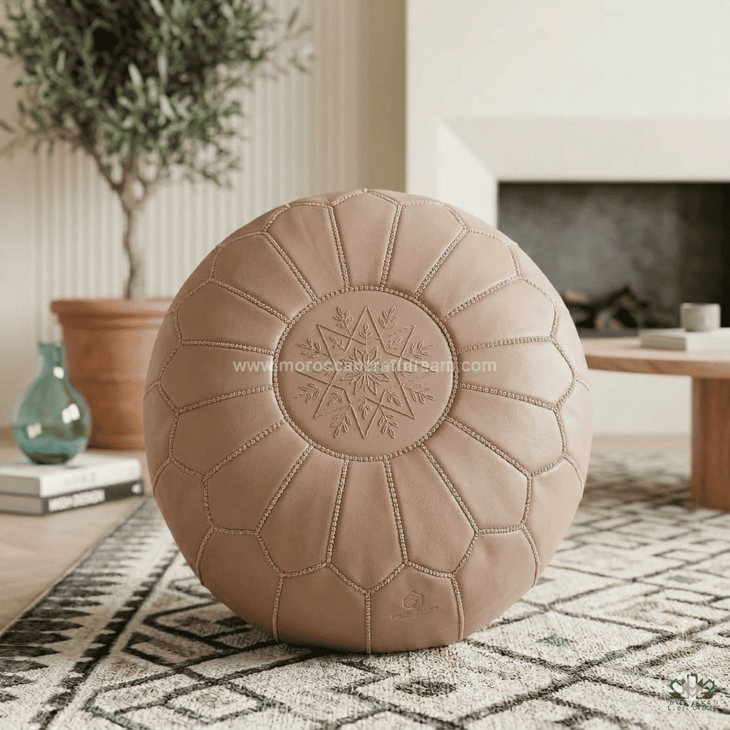 Blush Beige leather pouf on a patterned rug with a blurred indoor background