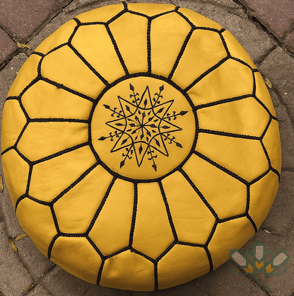 mustard leather moroccan pouf with geometric pattern on a stone pavement