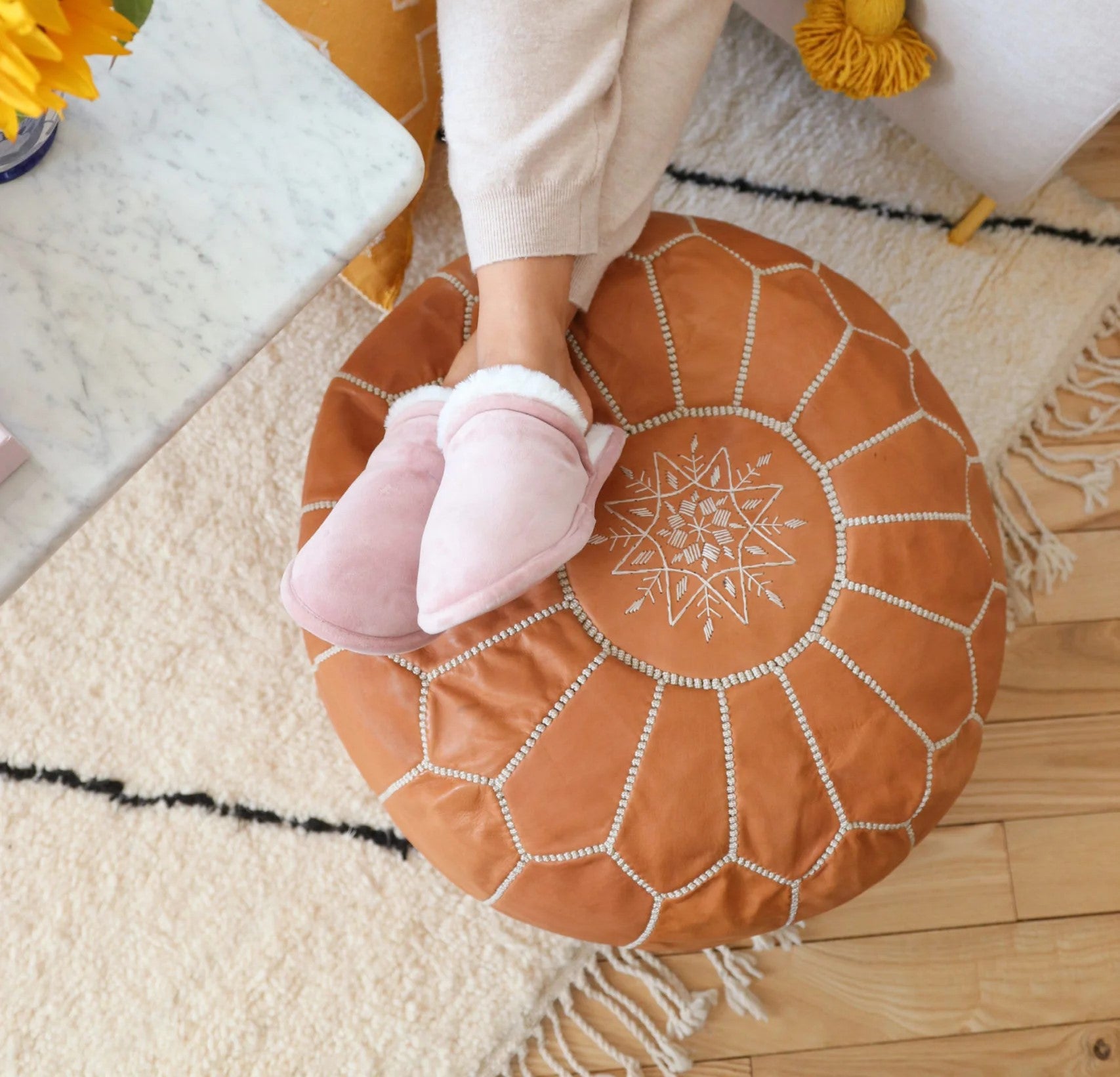 Handcrafted round leather ottoman used as foot stool & pouf with intricate Moroccan design, perfect for adding a touch of artisanal elegance to modern or bohemian home decor.