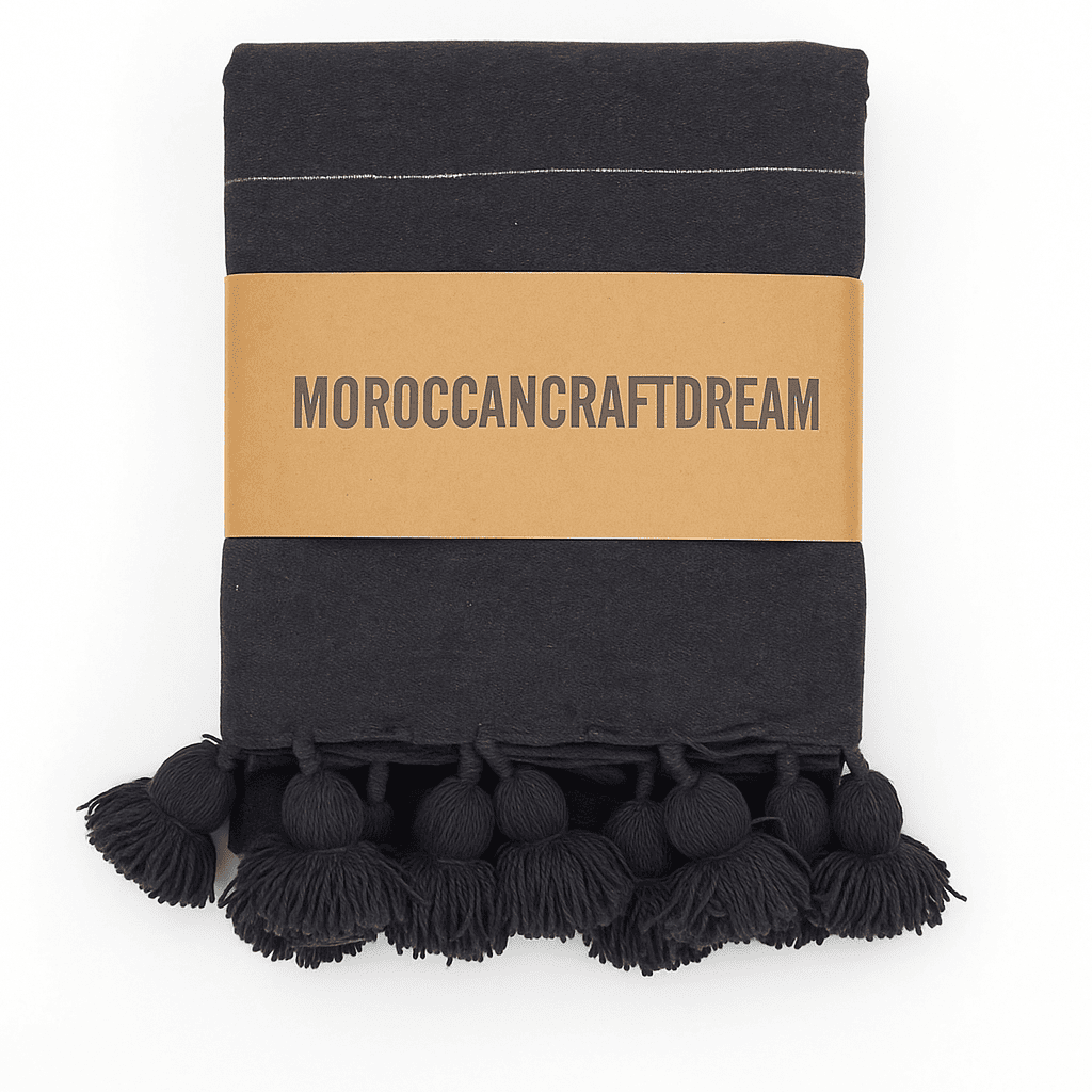 dark gray blanket with pom-pom trim and 'Moroccancraftdream' label on a white background