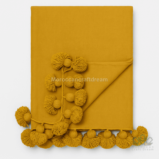 Mustard yellow fabric with pom-pom details on a white background