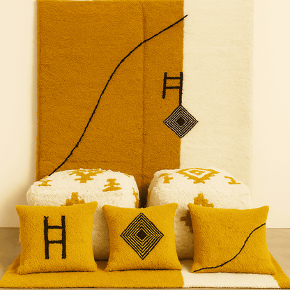 Decorative pillows with geometric patterns on a textured wall and surface.