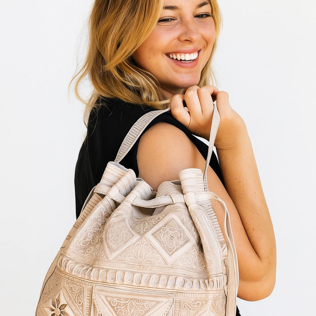 Woman holding a beige embroidered backpack against a white background