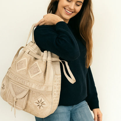 Woman holding a beige embroidered bag against a white background