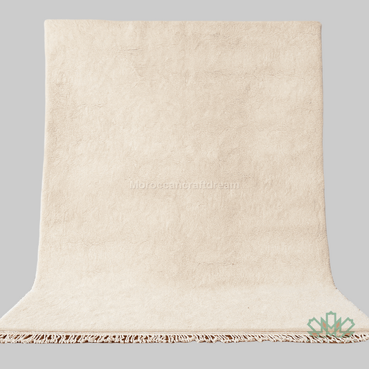 Beige textured rug with tassels on a wooden floor against a white wall.