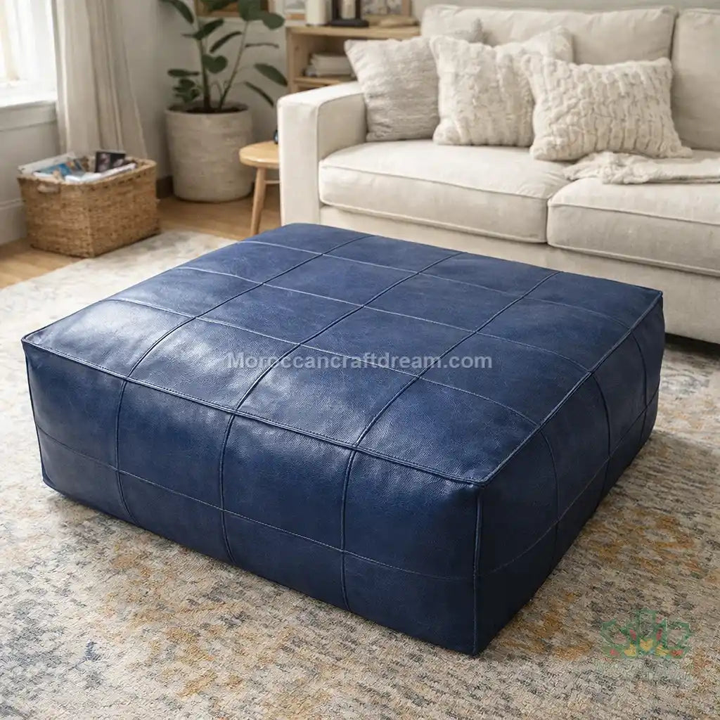 Navy Blue leather ottoman in a living room setting with a beige sofa and decor.