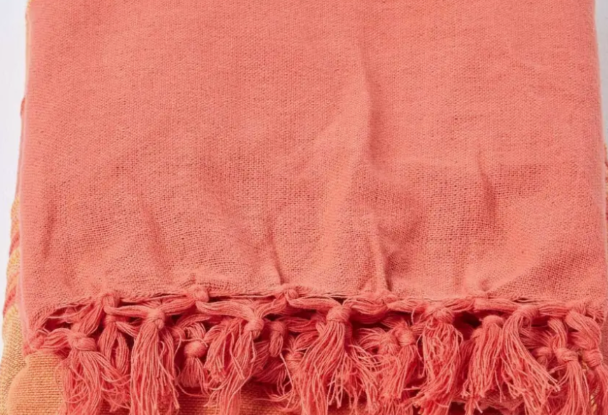 Coral-colored fabric with tassels on a white background