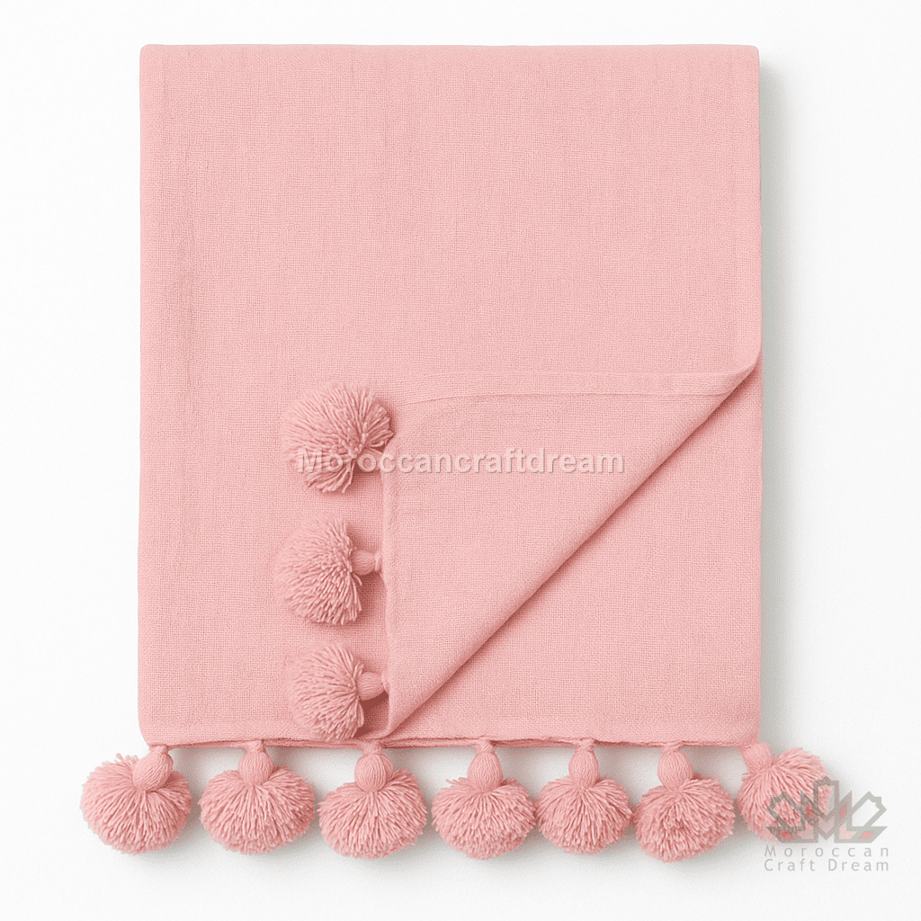 Pink blanket with pom-pom trim on a white background