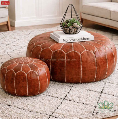 Two tan leather ottomans on a textured rug with a small table and decorative items.