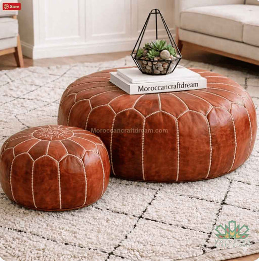 Two tan leather ottomans on a textured rug with a small table and decorative items.