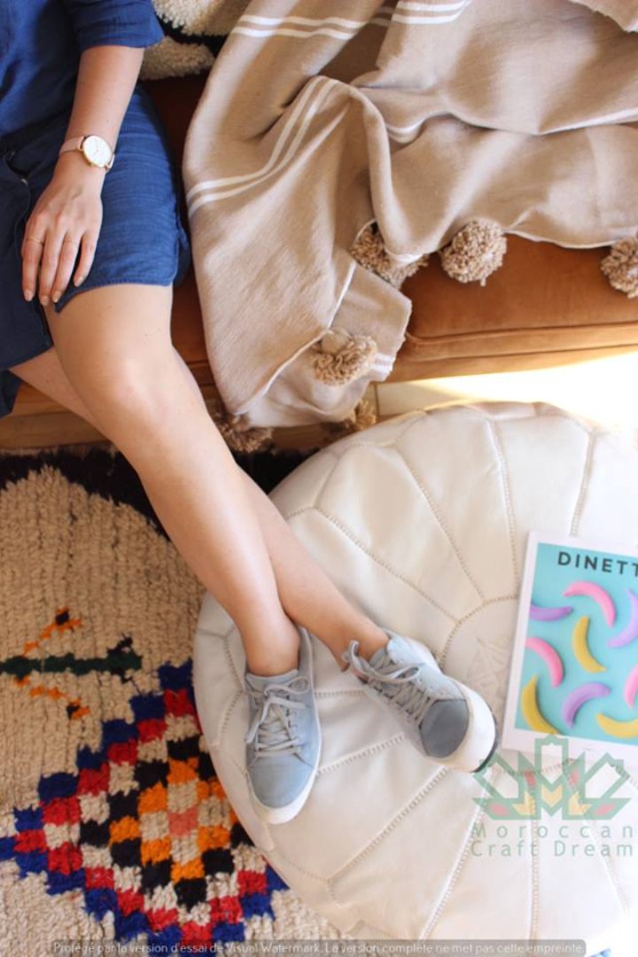 White Luxurious brown leather Moroccan pouf ottoman by Moroccancraftdream, used as a footrest or extra seating option.