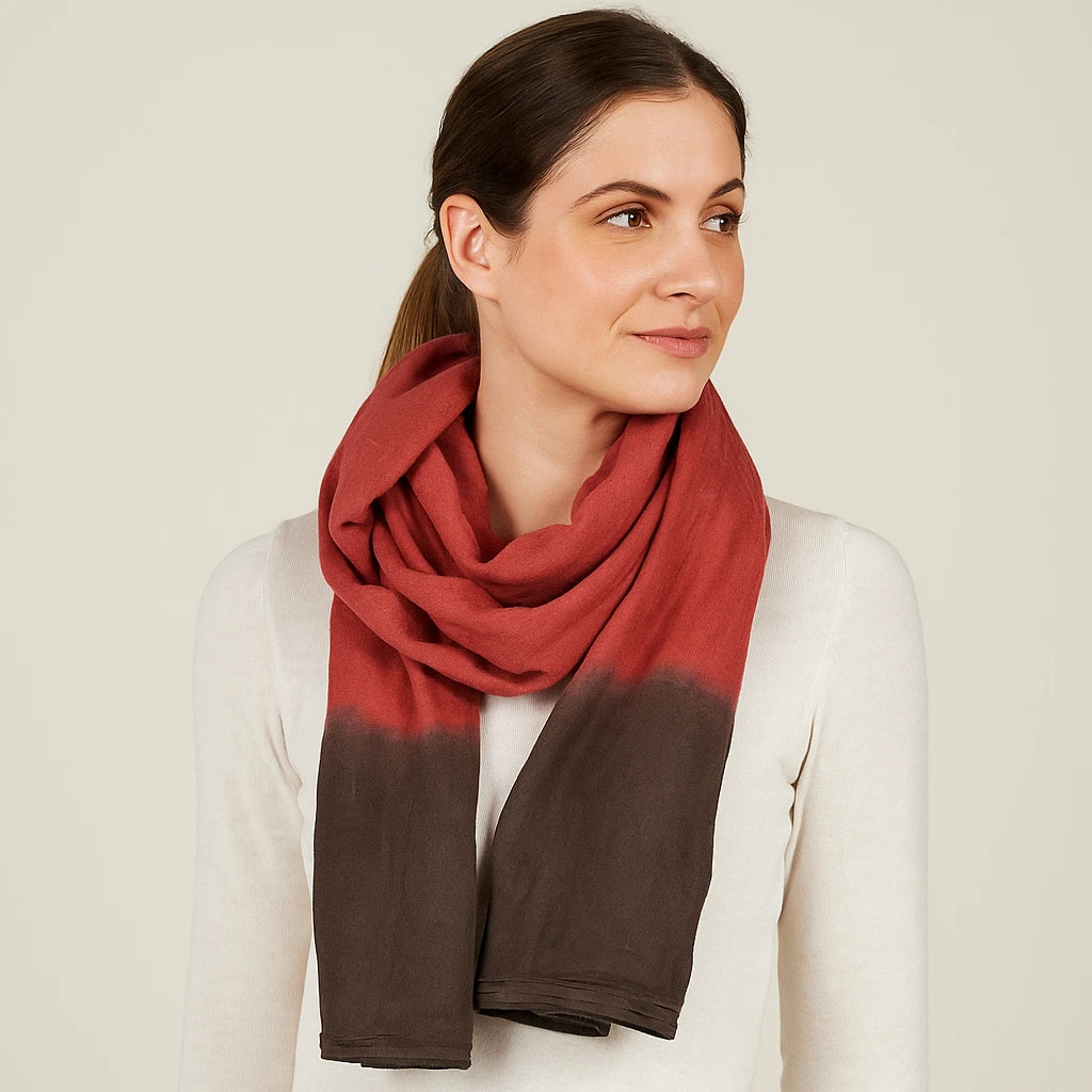 Woman wearing a red and brown gradient scarf on a plain background