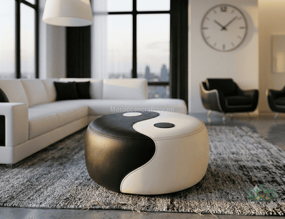 A modern round ottoman with a black and white yin-yang design, styled in a contemporary living room setting on a gray rug.