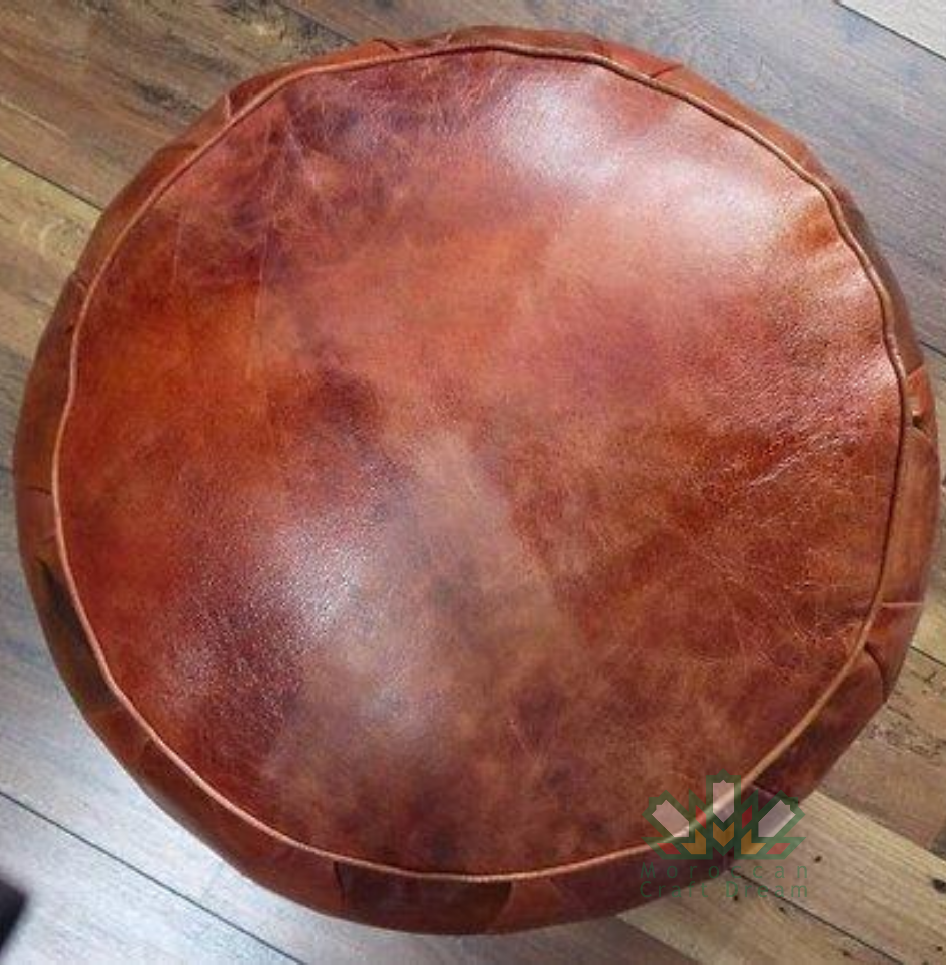 brown handmade round Moroccan pouf ottoman in genuine leather, perfect for use as a versatile coffee table or footrest. This Moroccan leather ottoman enhances living room decor with its elegant design and multifunctional use.