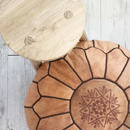 Round Moroccan leather poufs used as a coffee table, handcrafted with durable materials and traditional stitching in natural tones.