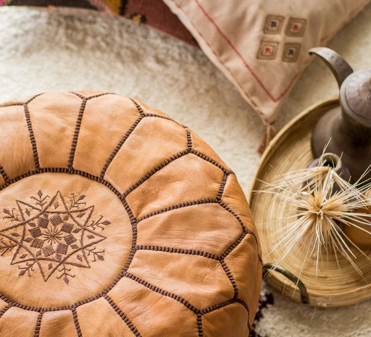 Round Moroccan leather poufs used as a coffee table, handcrafted with durable materials and traditional stitching in natural tones.