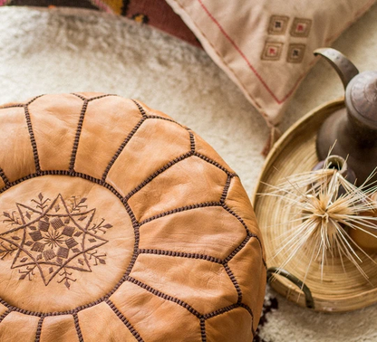 Round Moroccan leather poufs used as a coffee table, handcrafted with durable materials and traditional stitching in natural tones.